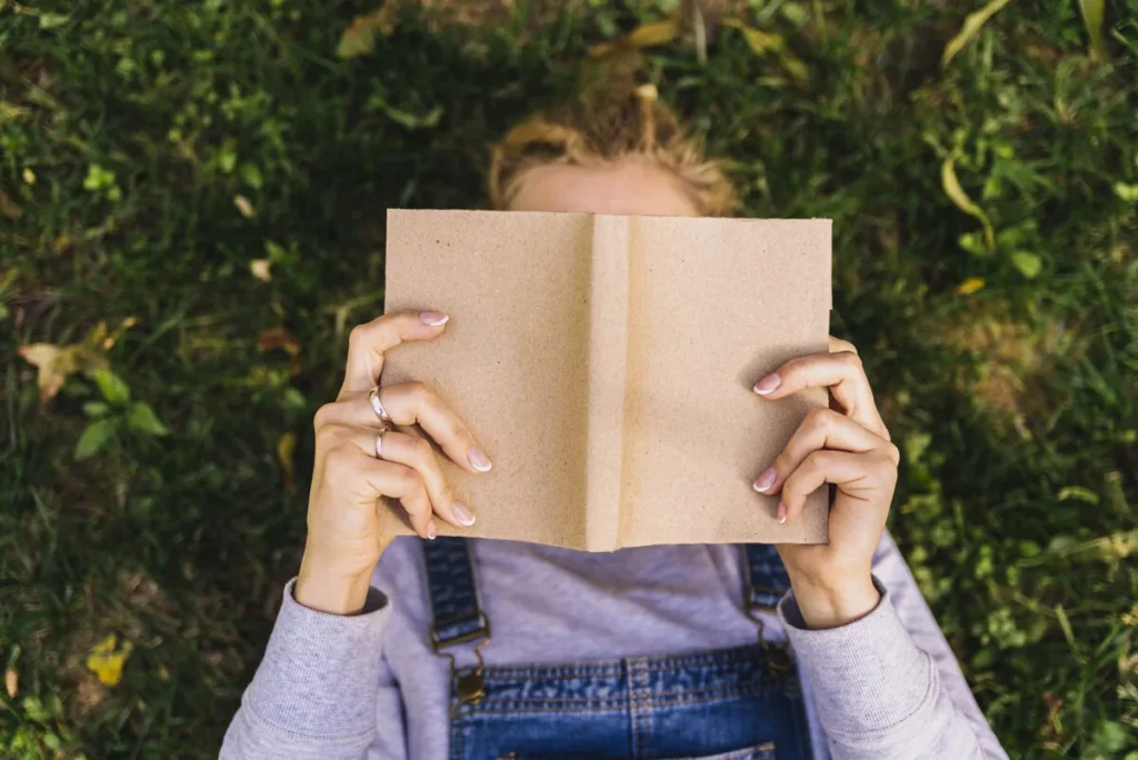 Imagen de mujer leyendo un libro en la hierba